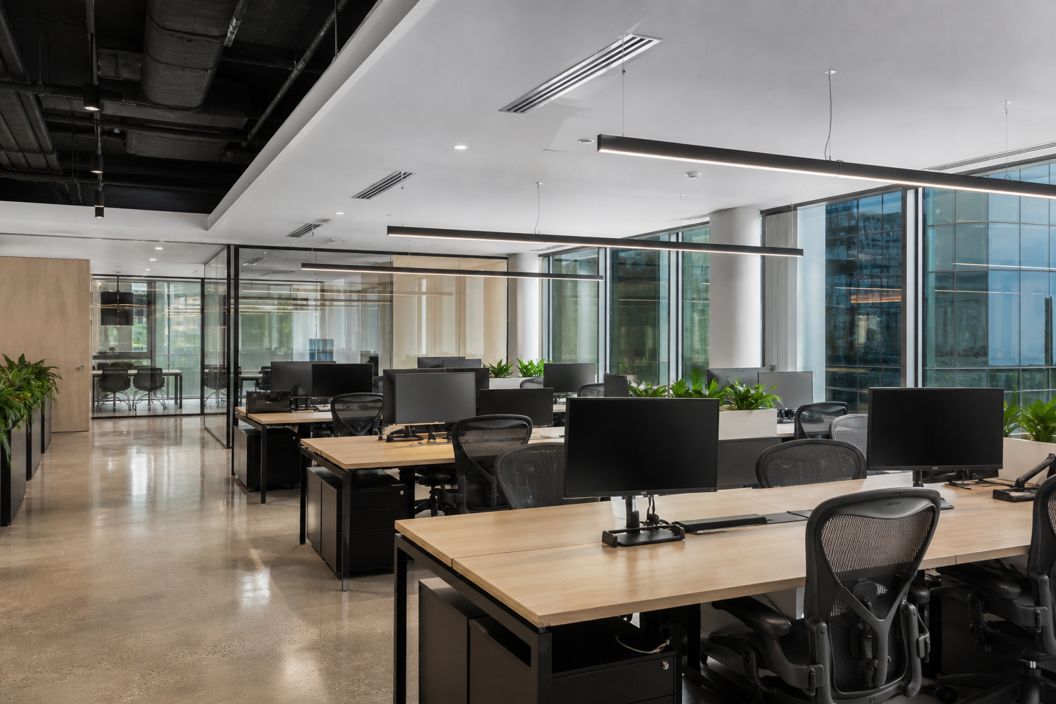 Finished open-plan office with desks, monitors and meeting room — ready before staff move in